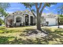 Beautifully landscaped single-story home with lush lawn, mature trees, and a spacious two-car garage at 6617 Cheswick St, Sarasota, FL 34243