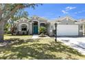 Charming single-story home boasts a well-manicured lawn, two-car garage, mature landscaping, and a vibrant turquoise front door at 6617 Cheswick St, Sarasota, FL 34243