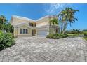 This exterior view showcases a two-story home with a beautiful paver driveway and attached two-car garage at 7728 Club Ln, Sarasota, FL 34238