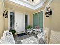Charming front porch with white seating set, stylish sconces, and tiled floor offers a warm welcome at 7728 Club Ln, Sarasota, FL 34238