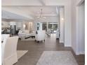 Bright and airy living room featuring wood-look floors, an elegant chandelier, and access to the pool area at 8133 Grande Shores Dr, Sarasota, FL 34240