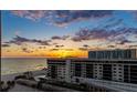 Oceanfront condo building view featuring beautiful gulf view at sunset with palm trees and beach access at 1212 Benjamin Franklin Dr # 909, Sarasota, FL 34236