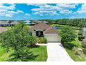 Aerial view of a single Gathering home featuring a well-manicured lawn, mature landscaping, and a serene pond at 12815 24Th Street E Cir, Parrish, FL 34219