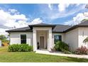 Inviting home featuring a manicured lawn, lush greenery, and a covered front porch at 1375 Norwalk Ter, Port Charlotte, FL 33953