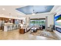 Open-concept living area featuring a tray ceiling, tile flooring, and expansive windows overlooking the lake at 20359 Cristoforo Pl, Venice, FL 34293
