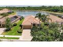 Beautiful front exterior with brick paver driveway, terra cotta roof, manicured lawn, and lake view in the back at 207 Winding River Trl, Bradenton, FL 34212
