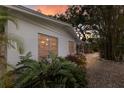 Exterior view of the home featuring a white exterior, large windows and lush greenery at 2207 Hickory Ave, Sarasota, FL 34234