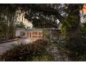 Charming home featuring mature trees, lush landscaping, and a welcoming, light-filled facade at 2207 Hickory Ave, Sarasota, FL 34234