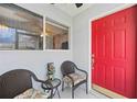 Inviting front porch with seating area, red door, and a decorative tiki statue at 3662 Bonaventure Ct, Sarasota, FL 34243