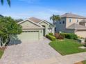 Inviting one-story home with lush landscaping, a brick driveway, and a convenient two-car garage at 3740 Summerwind Cir, Bradenton, FL 34209
