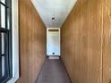 Hallway view showcasing wood paneled walls, with a white front door at the end, and a window to the left at 3957 Bearded Oaks Ct, Sarasota, FL 34232