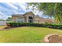 A lush, green front lawn is bordered by well-kept landscaping featuring vibrant flowers and mature trees near the tan home at 4211 30Th E Ln, Bradenton, FL 34208