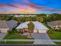 Stunning aerial view of the property showcasing its white roof, three car garage and landscaped surroundings at 490 Pine Lily Way, Venice, FL 34293