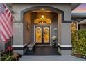 Inviting entryway featuring double doors with decorative wreaths, bench, and beautiful stonework at 490 Pine Lily Way, Venice, FL 34293