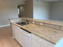 Kitchen island with stainless sink, granite countertops, and white cabinetry at 5330 Hyland Hills Ave # 2314, Sarasota, FL 34241