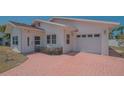 Paver driveway leading to a single-car garage and covered entry of the light colored home at 5522 Calle Del Verano, Sarasota, FL 34242