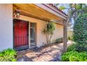 Inviting covered entrance features brick pavers, vibrant red door, and adjacent mature landscaping at 6412 Sun Eagle Ln, Bradenton, FL 34210