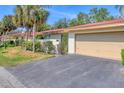 Villa featuring manicured greenery, a terra cotta roof, and an attached two-car garage at 6412 Sun Eagle Ln, Bradenton, FL 34210