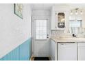 Bright kitchen with wainscoting, white cabinets, and modern appliances near a back door at 1005 45Th E Ave, Ellenton, FL 34222