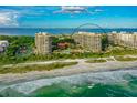 A high-angle aerial shot features beachfront condos with lush greenery and sandy shores near crystal clear waters at 1241 Gulf Of Mexico Dr # 803, Longboat Key, FL 34228