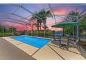 Stunning screened pool with a gorgeous sunset view over the lake, accompanied by outdoor seating and lush landscaping at 13167 Fernando St, Venice, FL 34293