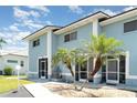 Exterior view of the condo with a private entrance, sidewalk, and tropical landscaping, including palm trees at 1424 Mediterranean Dr # 112, Punta Gorda, FL 33950