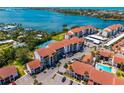 Beautiful aerial shot showcasing waterfront condos with red tile roofs, a community pool, and ample parking at 1624 Stickney Point Rd # 204, Sarasota, FL 34231