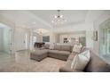Open-concept living room with a sectional sofa, white walls, tile flooring, and a view of the kitchen at 17449 Sandpearl Rd, Venice, FL 34293