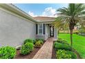 Inviting front entrance with brick pathway, manicured landscaping, and charming shuttered windows at 19038 Lappacio St, Venice, FL 34293