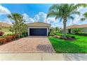 Charming single-story home with brick driveway, black garage door, palm trees, and well-manicured landscaping at 19038 Lappacio St, Venice, FL 34293