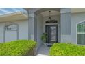 Elegant front entrance with decorative glass door, lush landscaping, and stylish outdoor lighting at 4037 Wooley Ave, North Port, FL 34287
