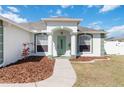 Inviting front entrance with green door, pillars, and lush landscaping at 5909 33Rd E Dr, Palmetto, FL 34221
