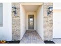 Inviting entryway with stone-accented columns, decorative lighting, and a brick-paved walkway at 620 Nasturtium Ct, Nokomis, FL 34275