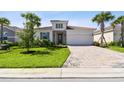 Charming one-story home featuring a brick-paved driveway, lush green lawn, and neatly trimmed palm trees at 620 Nasturtium Ct, Nokomis, FL 34275