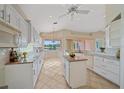 Bright kitchen featuring white cabinets, an island, granite countertops, tile flooring, and views of the lake at 6408 Rookery Cir, Bradenton, FL 34203
