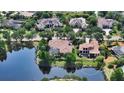 Stunning aerial view of a luxury home with a pool, surrounded by mature trees and a serene lake at 8016 Bounty Ln, Bradenton, FL 34202