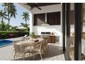 Outdoor kitchen and dining area featuring a built-in grill, dining table, and access to pool at 838 Norsota Way, Sarasota, FL 34242