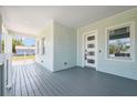Inviting front porch with a modern door and windows, featuring a smooth gray porch and light turquoise siding at 8622 Inwood Dr, Hudson, FL 34667