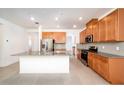 Bright kitchen features an island with granite countertops, wooden cabinets, and stainless steel appliances at 10171 Milky Way Cir, Sarasota, FL 34241