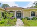 Charming home featuring a welcoming front entrance with beautiful columns and lush landscaping at 18026 Nutcracker Rd, Weeki Wachee, FL 34614