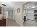 Bright hallway with tile floors leading to a well-lit kitchen and a bathroom at 2749 Riverbluff Pl # V65, Sarasota, FL 34231