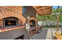 Covered outdoor kitchen featuring a brick pizza oven, wood storage, and a cozy dining area at 4857 Stevens Dr, Sarasota, FL 34234