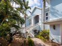 Beautiful light blue home featuring an elegant staircase, tropical landscaping and a paver walkway at 5132 Jungle Plum Rd, Sarasota, FL 34242
