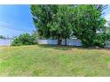 Spacious backyard featuring lush green grass, mature trees, and a privacy fence, perfect for outdoor activities at 5710 16Th W St, Bradenton, FL 34207