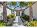 Inviting front entrance with beautiful landscaping and a paved walkway leading to the home's doorway at 5985 Amberly Dr, Bradenton, FL 34208
