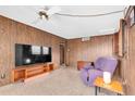 Cozy living room featuring wood paneling, a ceiling fan, and retro terrazzo flooring for a nostalgic touch at 6628 Auburn Ave, Bradenton, FL 34207
