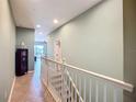 Hallway shows open railing, light green walls, tile floors, and a glimpse into the living area in neutral tones at 7346 Skybird Rd # 417, Bradenton, FL 34209