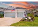 Home exterior boasting a manicured lawn, two-car garage, and patriotic American flag at 13169 Steinhatchee Loop, Venice, FL 34293