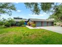 Brick home featuring a three-car garage, manicured lawn, and mature landscaping at 140 Cowpen Ln, Sarasota, FL 34240