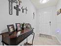 Home entryway decorated with dark wood console table and neutral-colored tile flooring at 16746 Parker River St, Wimauma, FL 33598